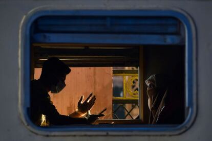 Dos pasajeros con mascarillas esperan el arranque de un tren hacia Rawalpindi, tras la relajación de las medidas de confinamiento por la pandemia de coronavirus, en Lahore (Pakistán).