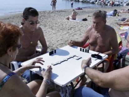 Varios jubilados juegan al dominó en una playa en Barcelona