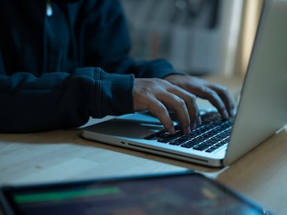 Un programador escribiendo en el teclado portátil para registrar el sistema de datos.