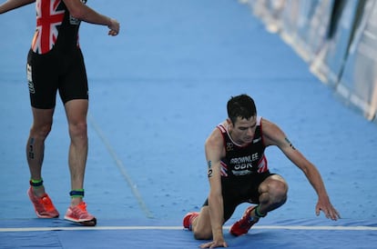 Jonathan Brownlee (derecha) cae cruzar la meta de la la isla de Cozumel, a la que llegó izado por su hermano Alister (izquierda).