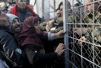 Los refugiados sirios luchan para entrar en Macedonia a través de un estrecho paso fronterizo con policías macedonios que intentan cerrar la puerta.