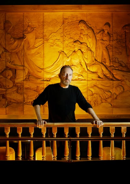 Rosa-Violán at the entrance of the restaurant, photographed in front of a 17th-century boiserie mural with references to the Silk Road. 