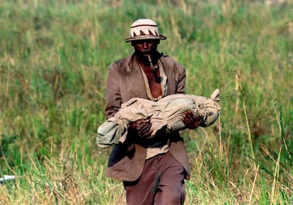 Un refugiado se dirige a una fosa común con el cuerpo de su hijo, un bebé muerto por cólera, el 29 de julio de 1994.