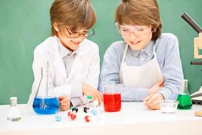 Two elementary-age children collaborate on various science experiments.  They are using a microscope, scale, chemical glassware, chemicals.  Imagination, creativity, inspiration for these little chemists!  DNA molecule.  Chalkboard, classroom setting.