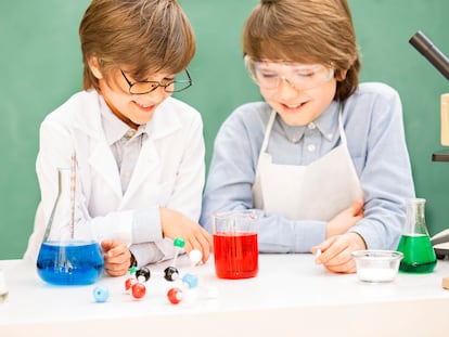 Two elementary-age children collaborate on various science experiments. They are using a microscope, scale, chemical glassware, chemicals. Imagination, creativity, inspiration for these little chemists! DNA molecule. Chalkboard, classroom setting.
