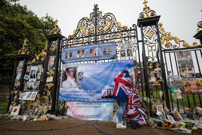 Dos personas se acercan a la verja de la entrada del palacio de Kensington donde se están depositando flores y mensajes con motivo del 20 aniversario de la muerte de Diana de Gales, en Londres.
