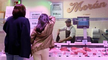 Un carnicero atiende a unos clientes en una galería comercial de Madrid.
