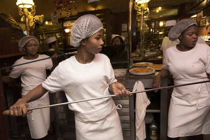 Tres migrantes reciben formación en un restaurante.