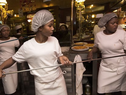 Tres migrantes reciben formación en un restaurante.