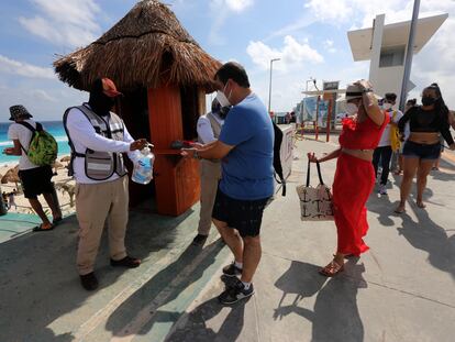 Un hombre reparte líquido desinfectante a turistas en Cancún (México).