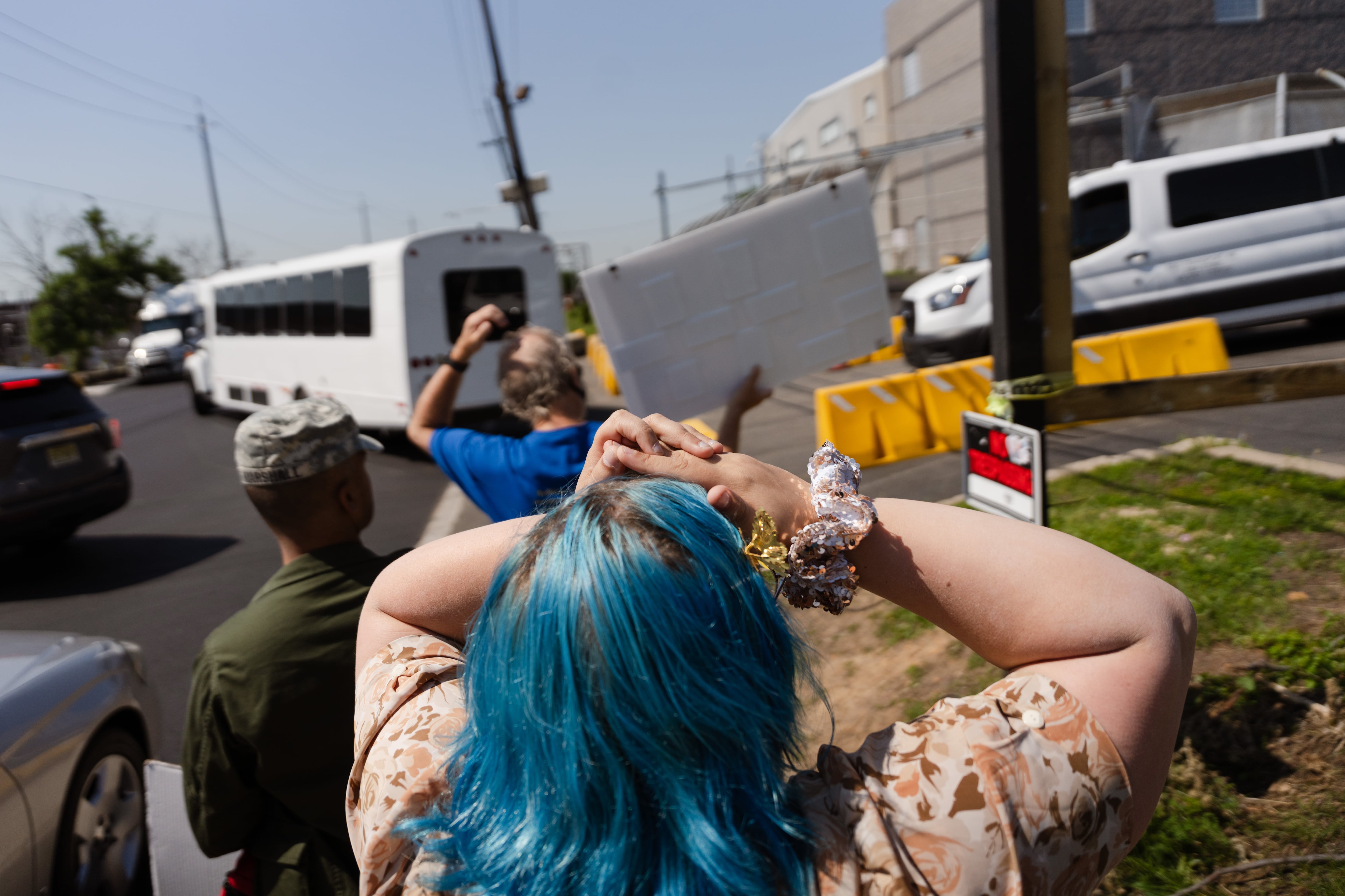 Una caravana con migrantes detenidos salen del centro Delaney Hall mientras activistas protestan en la entrada.