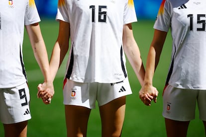 Jule Brand, Giulia Gwinn y Sjoeke Nuesken se dan la mano mientras suena el himno de su país, antes de disputar el partido de fútbol por el bronce ante España.