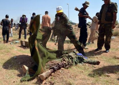 Rebeldes libios cubren un cadáver tras los enfrentamientos en Qawalish