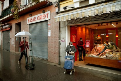 Varias personas pasan ante una tienda de alimentación en L'Hospitalet de Llobregat.