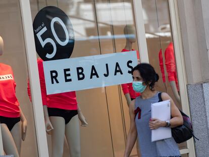 Una mujer pasa el viernes pasado frente a un escaparate de una tienda con carteles de descuentos.