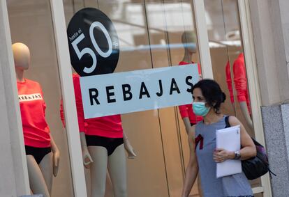 Una mujer pasa el viernes pasado frente a un escaparate de una tienda con carteles de descuentos.