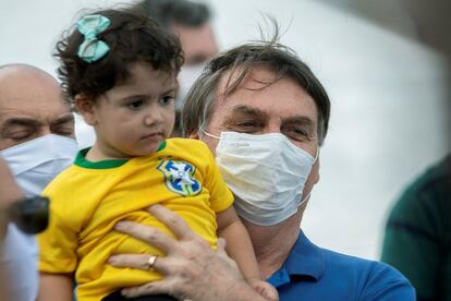 Bolsonaro segura uma menina na manifestação deste domingo na entrada do Palácio do Planalto, em Brasília. O presidente foi acompanhado por onze ministros e destacou a grande presença de seguidores, apesar das medidas do Governo regional para evitar aglomerações, como uma ferramenta para combater a covid-19. "Emocionante, uma manifestação espontânea, pacífica, seguindo boas práticas, sem nenhuma faixa agressiva a quem quer que seja. Um pessoal que tem a democracia, a liberdade e o patriotismo acima de tudo", repetiu o presidente em rede social.