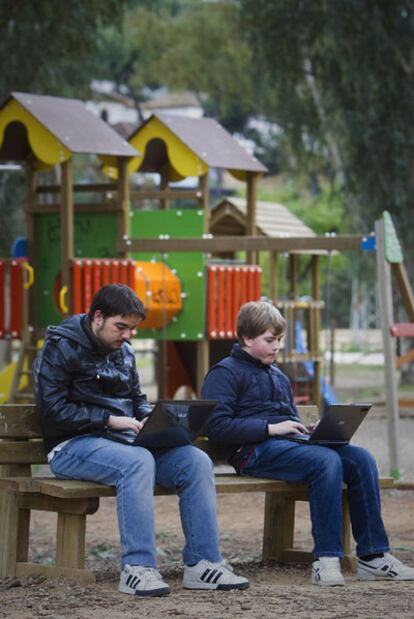 Dos adolescentes con sus portátiles en un parque infantil de Sevilla.