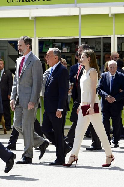 Hace dos años, en 2017, doña Letizia estuvo acompañada por el rey Felipe VI en el acto de inauguración de la Feria del Libro de Madrid. Con un conjunto blanco de blusa y pantalón y unos zapatos granates a juego con el bolso de mano, la Reina paseó por todas las casetas colocadas en el Parque del Retiro de la capital. 