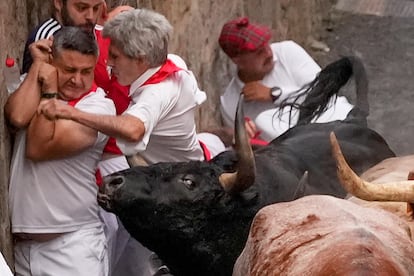 Varios mozos son aprisionados por uno de los toros de la ganadería de Jandilla, durante el sexto encierro de los Sanfermines.
