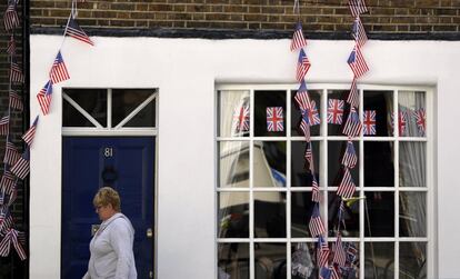 Una mujer pasa por delante de una casa decorada con banderas británicas y estadounidenses por el enlace de Enrique y Meghan Markle. 