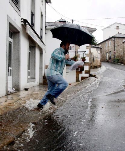 Un hombre intenta atravesar una calle de Cervo, una de las poblaciones afectadas por las inundaciones causadas por las fuertes lluvias que se están registrando en varios puntos de la provincia de Lugo.