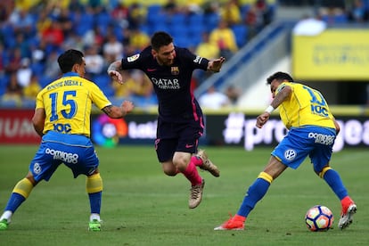 El jugador del Barcelona Leo Messi trata de pasar entre los jugadores de Las Palmas Roque Mesa y Momo, en una acción del partido.