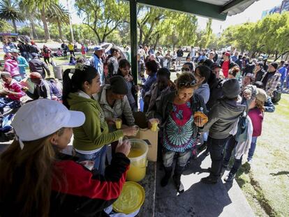 Ciudadanos cubanos que esperan en Quito un visado para viajar a Estados Unidos hacen cola para recibir comida y bebida.
