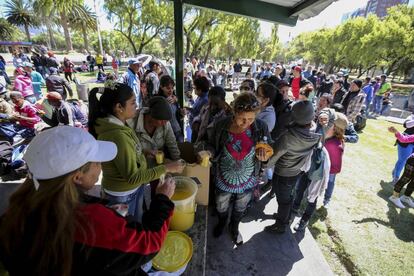 Ciudadanos cubanos que esperan en Quito un visado para viajar a Estados Unidos hacen cola para recibir comida y bebida.