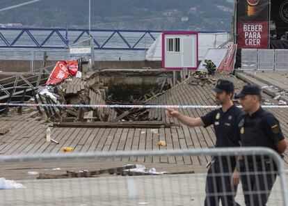 Dos agentes de Policía Nacional caminan frente a la pasarela desplomada en Vigo.