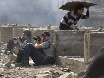 Dos fotógrafos extranjeros se resguardan de una batalla de piedras entre manifestantes a favor y en contra de Mubarak en El Cairo.