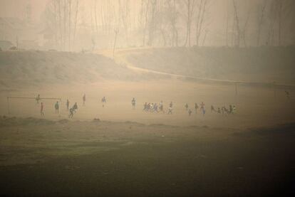 Jóvenes de la Cachemira india juegan a fútbol en un día con niebla en Srinagar. 