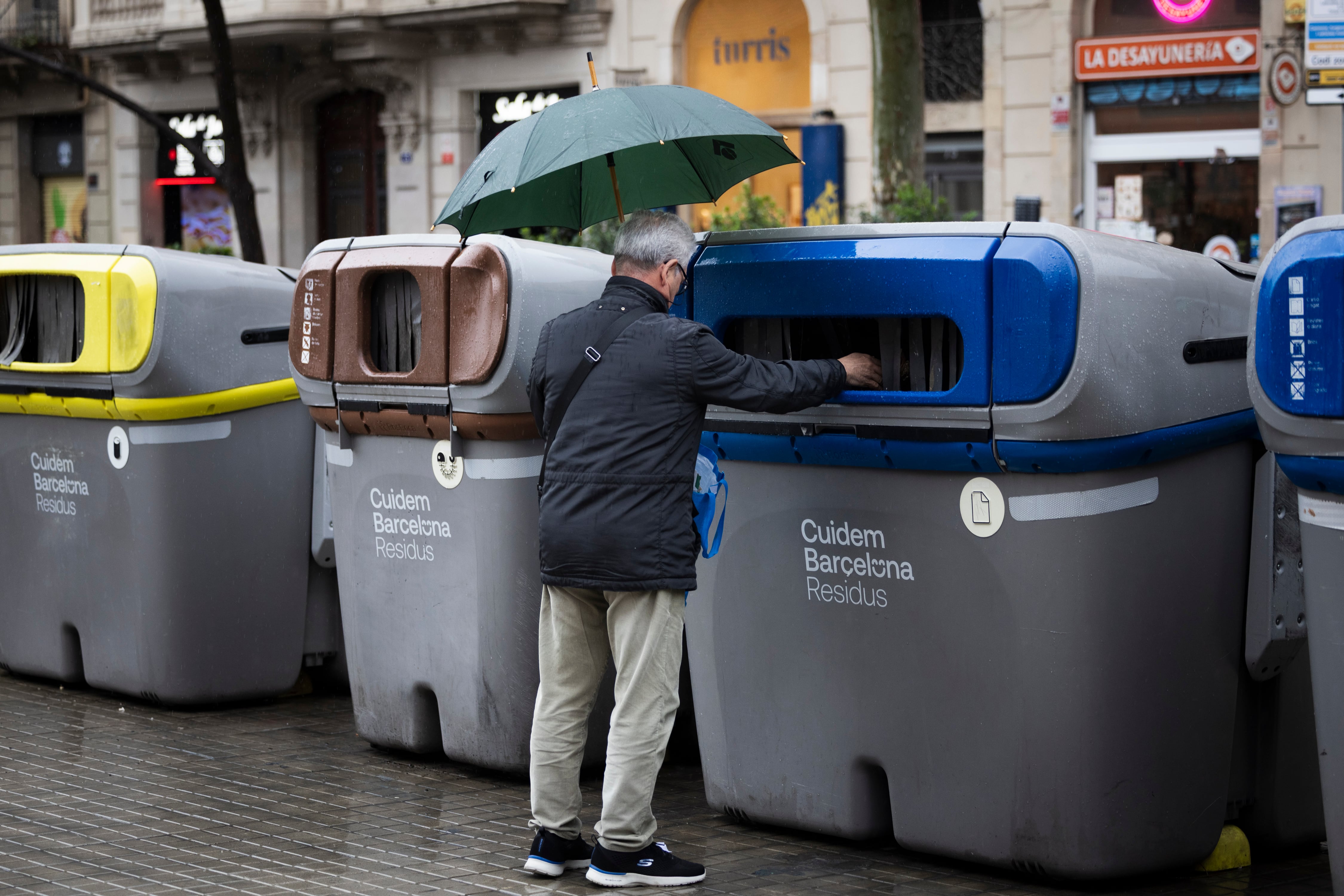 Un hombre recicla papel en un contenedor en el Eixample de Barcelona, el pasado febrero.