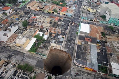 Imagen aérea de un gran socavón en Ciudad de Guatemala tras el paso de la tormenta tropical Agatha. Las autoridades guatemaltecas calculan que el agujero mide 20 metros de  diametro y unos 30 metros de profundidad. Vecinos del barrio ya habían denunciado ciertos ruidos procedentes del subsuelo en los días previos a la tormenta y ya se ha abierto una investigación para determinar el origen del gran socavón.  <a href="http://www.elpais.com/fotogaleria/tormenta/tropical/Agatha/arrasa/America/Central/elpgal/20100531elpepuint_2/Zes/2" target="_blank">Más fotografías de los estragos causados por Agatha</a> .