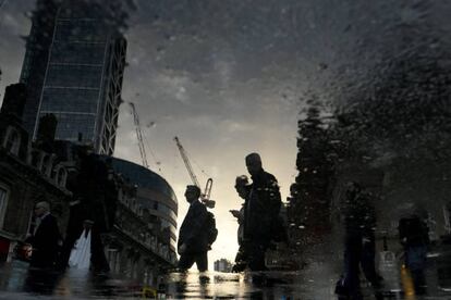 Trabajadores de la City de Londres se reflejan en un charco mientras se dirigen a sus puestos de trabajo.