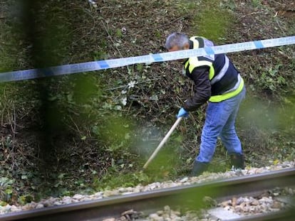 Un polic&iacute;a busca pruebas en las inmediaciones del apeadero ferroviario de La Arga&ntilde;osa, a las afueras de Oviedo.