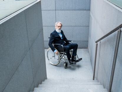Una persona con discapacidad frente a una escalera.