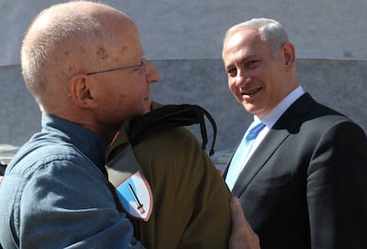 El padre de Gilad Shalit abraza a su hijo en presencia del primer ministro Netanyahu tras su llegada a la base aérea de Tel Nof, en una imagen proporcionada por el Gobierno de Israel.