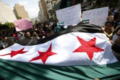 Manifestantes anti-El Asad ondean una antigua bandera siria este viernes en Beirut (L&iacute;bano).