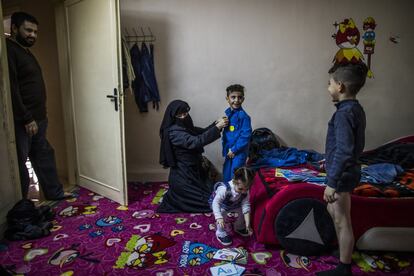 Hanan, la madre, ayuda a sus hijos a vestirse para ir al colegio jordano mientras Shams, la bebé, juega. La mayoría de personas que han huido del conflicto sirio no viven en los campos de refugiados sino en las zonas más deprimidas de la ciudad.