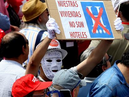 Un hombre sostiene un cartel bajo el lema "Stop pisos turísticos" durante la manifestación del Primero de Mayo, en Madrid.