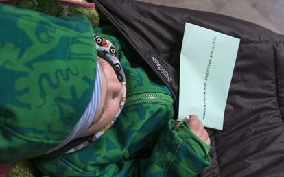 Un niño lleva la papeleta en su mano una papeleta para las votaciones, en un colegio electoral de Jaén.