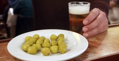 Un cliente ante una caña de cerveza y un plato de aceitunas en un bar de Madrid.