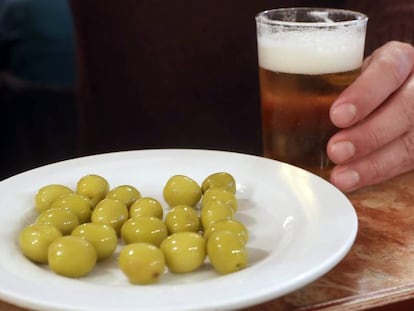 Un cliente ante una caña de cerveza y un plato de aceitunas en un bar de Madrid.