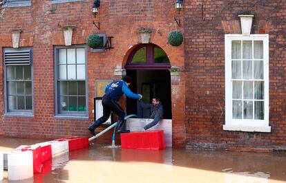 Un hombre se introduce en un restaurante rodeado de agua en Worcester, centro de Inglaterra. Miles de hogares permanecen sin luz por el temporal de lluvia y viento que azota al Reino Unido, donde las inundaciones han provocado un caos en los medios de transporte y el cierre de carreteras y puentes.