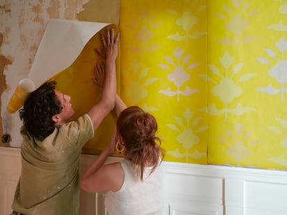Los expertos constatan que en 2023 se ha perdido el miedo al color para las paredes del hogar. En la imagen, una pareja coloca un papel pintado amarillo en una de las estancias de su casa.