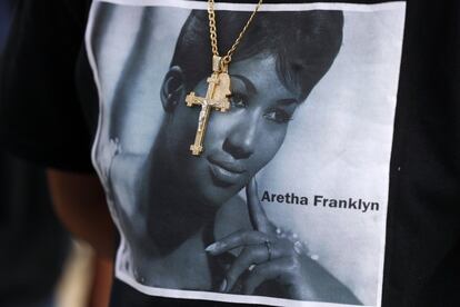 Una cruz de oro cuelga sobre la camiseta en homenaje a Aretha de una admiradora esperando afuera del Museo Charles H. Wright de Historia Afroamericana, durante una visita pública a la legendaria cantante en Detroit.