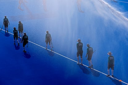 Un grupo de recoge pelotas camina sobre el campo de hockey antes del partido entre Sudáfrica y Alemania en el estadio  Yves-du-Manoir, este martes.