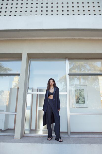 Trench de lana y mohair con cuello de piel de cordero,crop top de punto de seda acanalado; pantalón de lana y mohair con cremalleras, collar de piel de becerro negroy metal, y sandalias de cinta tejida y piel de becerro.