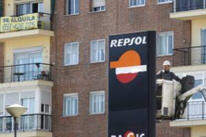 Un operario trabaja en un panel de Repsol en una gasolinera de Madrid. EFE/Archivo